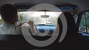 Young couple riding at vintage car during rainy wet weather. Unrecognizable man and woman sitting at the front seat of