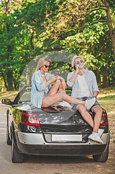 Young couple on road trip using smartphones. Modern lifestyle concept.