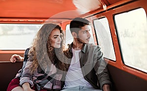 A young couple on a roadtrip through countryside, sitting in minivan.