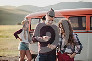 A young couple on a roadtrip through countryside, using map on smartphone.