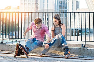 Young couple on rollerblades sitting.