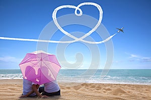 Young couple romantic kissing at the beach with the umbrella