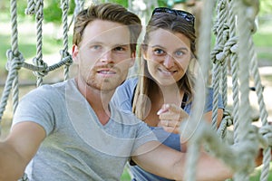 young couple on rope bridge activity course