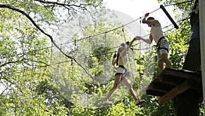 Young couple on a rope climbing in the adventure park