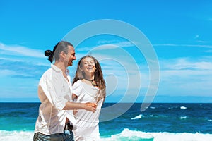 Young couple run by white sand beach along sea surf