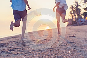 Young couple running along the sandy seashore in the rays of sunset, blurred image perfect background for travel agencies,