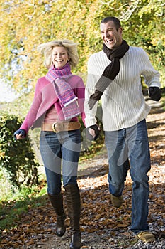 Young couple running along woodland path