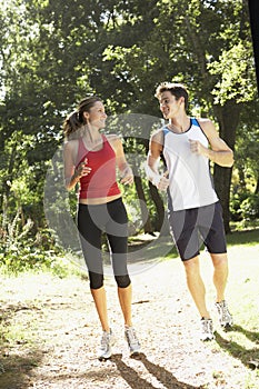 Young Couple Running Along Woodland Path
