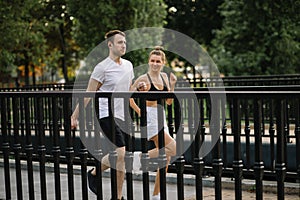 Young couple running in the city park, joint sports, cheerfulness, city lifestyle