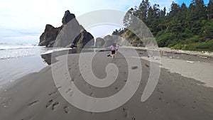 Young couple running with a dog on the coast of the ocean or sea.