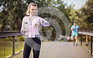 Young couple running in the park at morning. Woman timing her jogging male partner photo