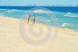 Young couple running on Sandy Hook Beach, New Jersey, USA.