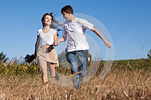 Young couple running on summer meadow