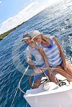 Young couple at sailboat wheel in caribbean sea