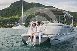 Young couple is sailing on a yacht in the Indian ocean. Man and woman sit on the edge of the yacht.