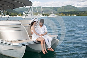 Young couple is sailing on a yacht in the Indian ocean. Man and woman sit on the edge of the yacht.