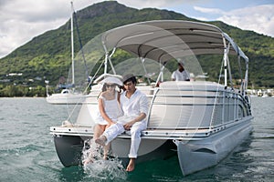 Young couple is sailing on a yacht in the Indian ocean. Man and woman sit on the edge of the yacht.