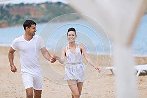 Young couple on sand seashore in cloudy day