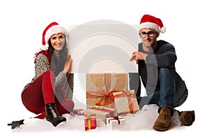Young couple in santa hat holding blank board for advertisement,
