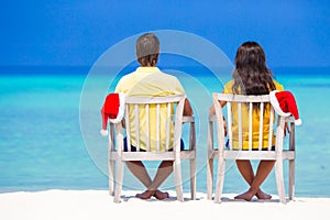 Young couple in Santa hats relaxing on tropical beach during Christmas vacation