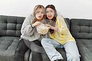 Young couple scared watching horror film eating popcorn at home