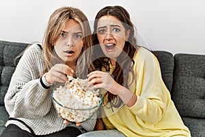 Young couple scared watching horror film eating popcorn at home