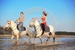 Young couple in the sea on horseback