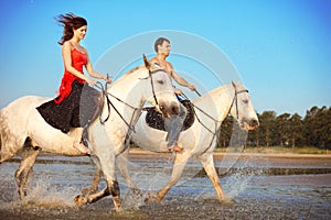 Young couple in the sea on horseback