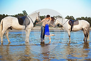 Young couple in the sea with horses