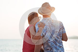 Young couple by the sea looking into the sun