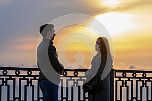 Young couple by the sea at sunset communicates while respecting social distance