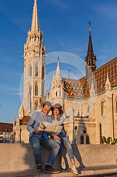 Young couple searching right direction on map from the point from Fisherman Bastion in Budapest with Matthias Church on