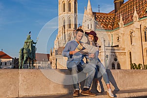 Young couple searching right direction on map from the point from Fisherman Bastion in Budapest with Matthias Church on