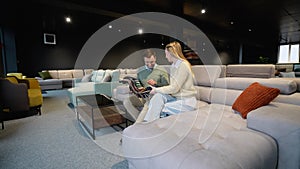 Young couple selecting together seat cover for sofa in furniture store