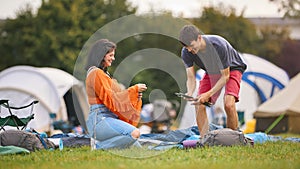 Young Couple Setting Up Tent At Summer Music Festival Unpacking Camping Equipment