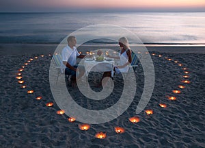 A young couple share a romantic dinner on the beach