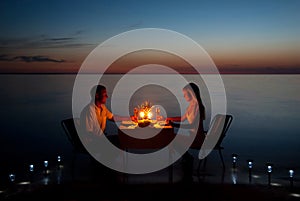 A young couple share a romantic dinner with candles on the beach