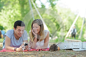 Young couple sharing earphones while picnicing in park
