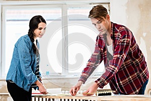 Young couple sharing tools while working on improvement of their house