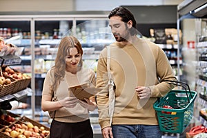 Young couple shopping for groceries in supermarket and holding paper bags