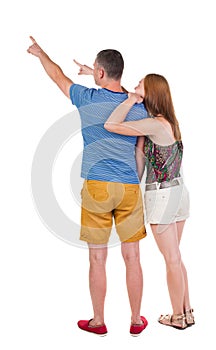 Young couple in short pointing at wal