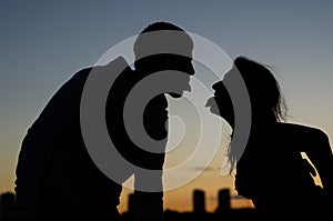 Young couple showing each other tongue against the evening city