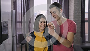 Young couple showing new home keys to camera