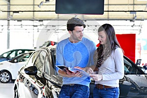 young couple in the showroom of a car dealership buying and testing vehicles