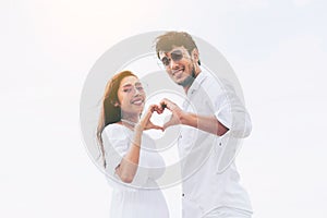 Young couple shows heart shape hand gesture.