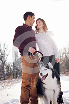 Young couple with siberian husky dog in winter in the park