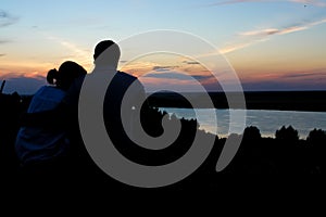 Young couple silhouette against sunset sky. Romantic evening.