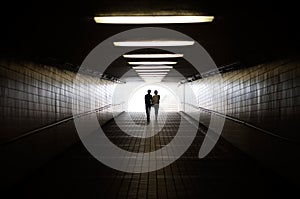 Young couple in silhouette walking towards exit of pedestrian underpass