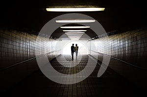 Young couple in silhouette walking towards exit of pedestrian underpass photo