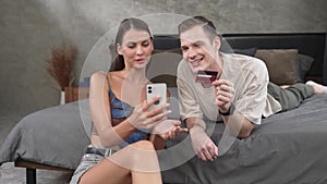 Young couple sit in the bed room using online payment app. Adit